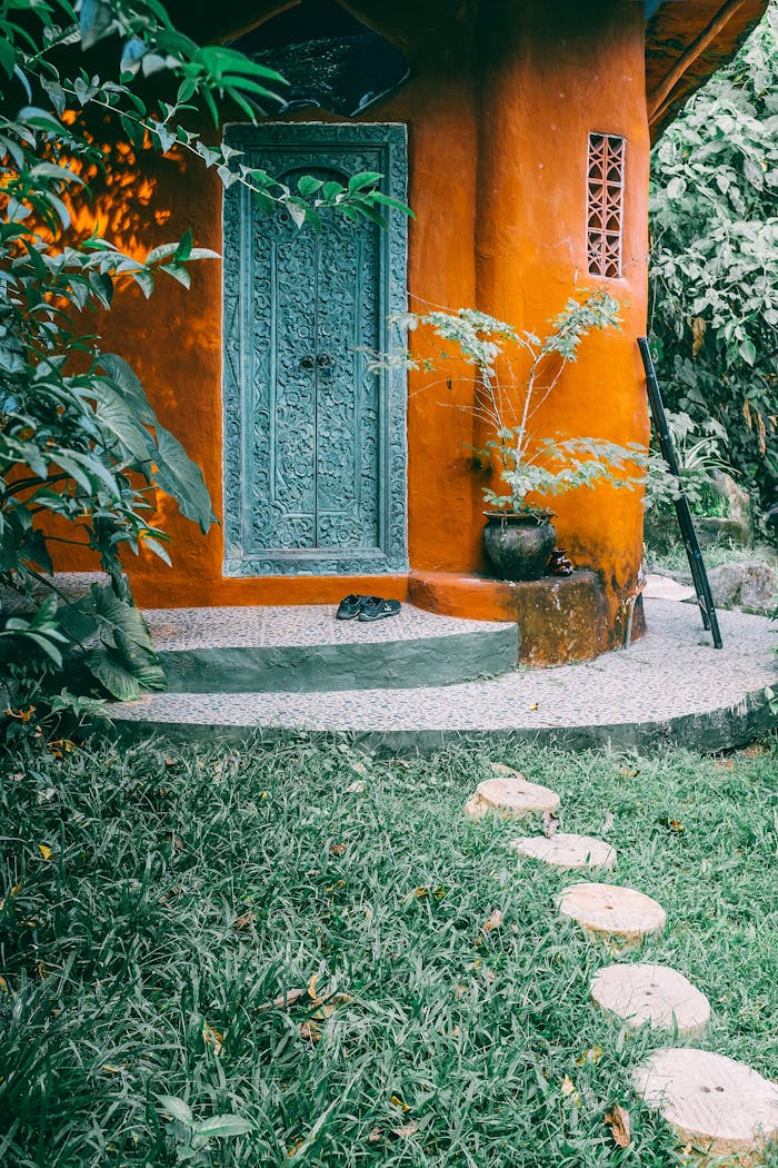Facade and front door of old stone bright yellow traditional house and green lawn with trees